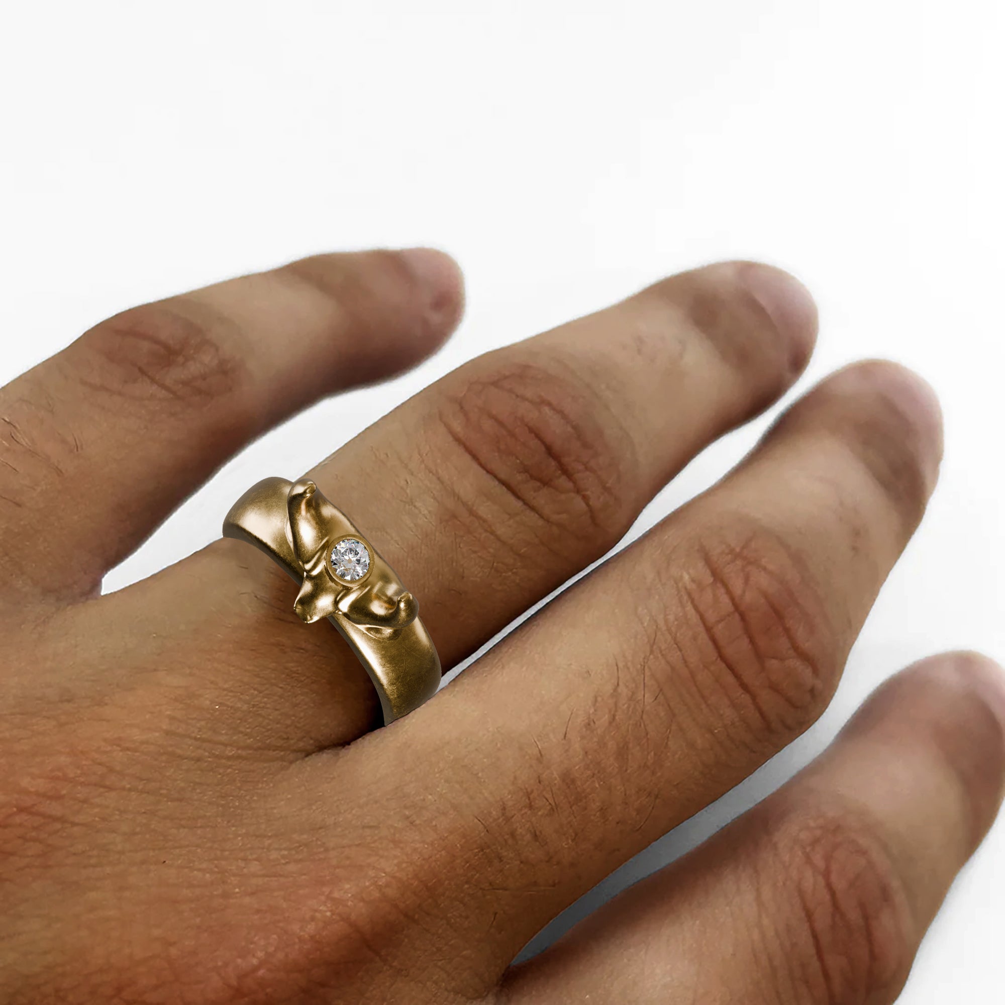 A hand holding a silver ring with a bull's head design and a small diamond.